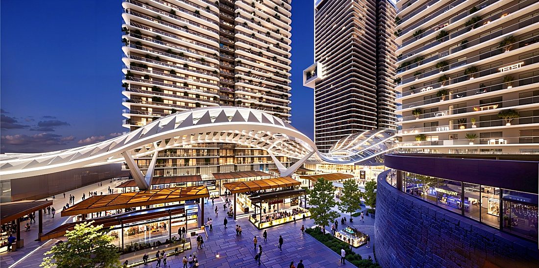 A ribbed white canopy arcing between two towers over a lit retail street