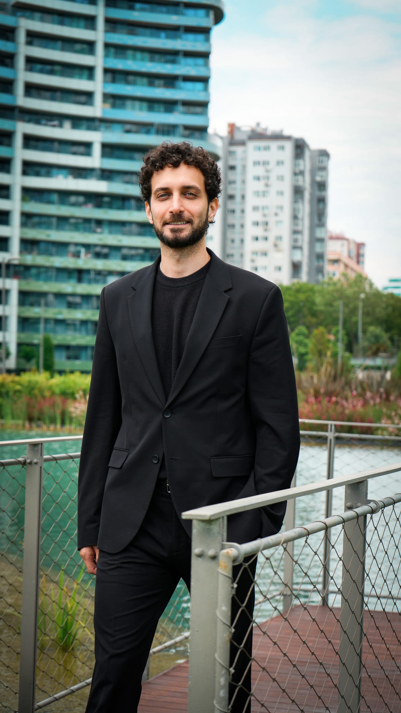 Erfan Naji on a waterfront boardwalk, residential towers of central Istanbul behind him